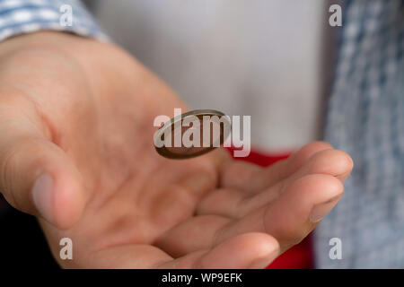 Immagine ravvicinata di mano lanciare una moneta, probabile e le possibilità di vincita concetto, fifty-fifty s Foto Stock