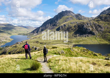 Due escursionisti escursioni sul percorso da Y Garn sopra Llyn Idwal guardare a vista del monte Tryfan e Ogwen Valley nel Parco Nazionale di Snowdonia. Ogwen Gwynedd Wales UK Foto Stock
