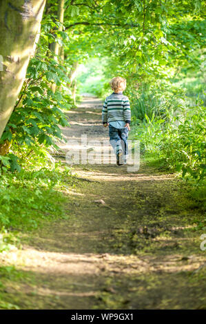 Un bambino felice che corre lungo un percorso nascosto nella Foresta di primavera Foto Stock