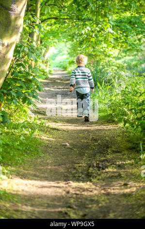 Un bambino felice che corre lungo un percorso nascosto nella Foresta di primavera Foto Stock