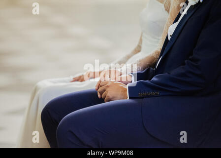 La giovane coppia tiene le mani durante il matrimonio Foto Stock