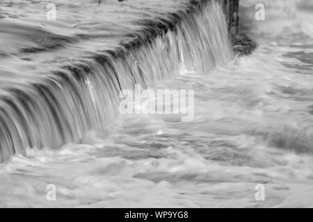 In bianco e nero fotografie astratte di un paesaggio marino con forte risacca con acqua che scorre su un pool di marea parete in corrispondenza di un otturatore a bassa velocità - potente Foto Stock