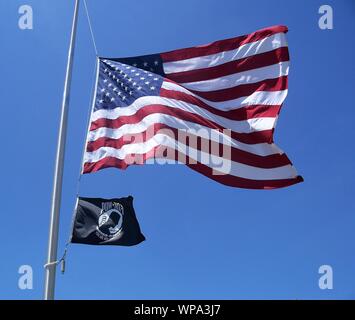 Stati Uniti d'America e prigioniero di guerra bandiere su un pennone con un cielo azzurro sullo sfondo Foto Stock