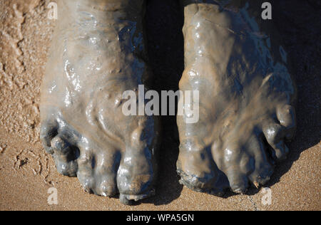 Piedi coperti di fango viscido fango su una spiaggia. Foto Stock