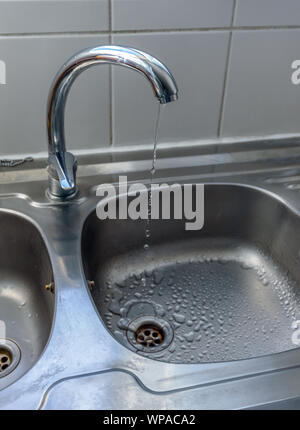 Acqua pulita gocce che cadono dal gocciolamento di un rubinetto di cucina, un inutile spreco di acqua in un mondo minacciato dalla scarsità d'acqua. Foto Stock