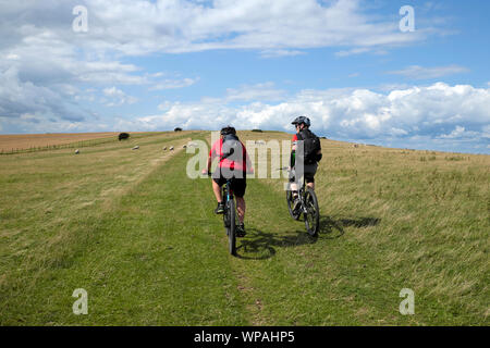 Due ciclisti equitazione biciclette su un sentiero fino alla cima di una collina sulla South Downs modo in East Sussex, Regno Unito Inghilterra KATHY DEWITT Foto Stock