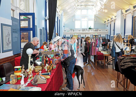 Lewes hall del mercato interno di commercianti che vendono mercanzia & man con il cane cercando di antiquariato in stallo in giorno di mercato nella città di Sussex England Regno Unito KATHY DEWITT Foto Stock