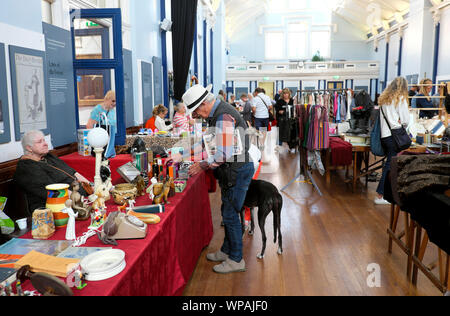 Lewes hall del mercato interno di commercianti che vendono mercanzia & man con il cane cercando di antiquariato in stallo in giorno di mercato nella città di Sussex England Regno Unito KATHY DEWITT Foto Stock