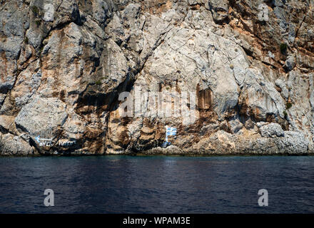 Isola di Symi, Grecia, Agosto 2019. Vista la bandiera greca dipinta sulla scogliera Foto Stock