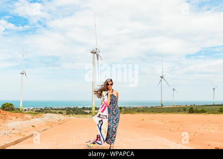 Donna e bambina supporto vicino alla turbina eolica azienda da energia pulita vicino al mare. Phan Rang, Vietnam. Foto Stock