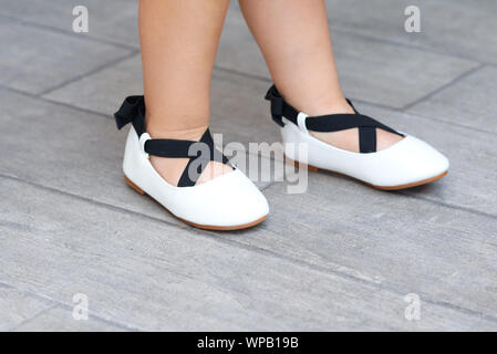 Close up carino bambina per le gambe in nuovi appartamenti. Bambina in una calzatura store. Il Toddler kid giocando ed esecuzione cercando ballerina scarpe in un supermercato. Foto Stock