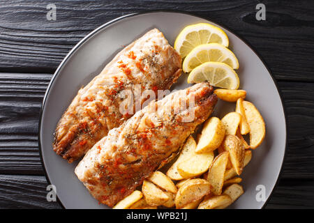Grigliata di sgombro filetto servito con patate fritte e le fette di limone closeup su una piastra sul tavolo. Parte superiore orizzontale vista da sopra Foto Stock
