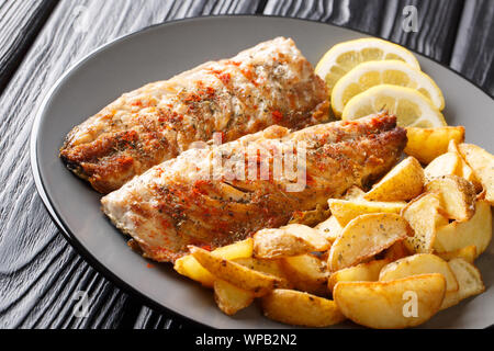 Grigliata di sgombro filetto servito con patate fritte e le fette di limone closeup su una piastra sul tavolo orizzontale. Foto Stock