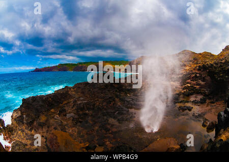 Foro di sfiato con la spruzzatura di acqua che è stato creato da Pacific Ocean Waves colpendo il tall scogliera rocciosa costa che è stato creato da lava a Maui, Hawaii, STATI UNITI D'AMERICA Foto Stock