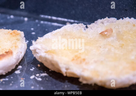 Tagliato e aperto rotoli imburrati e su un vassoio tostato con briciole nel vassoio. La strato imburrato è una dorata dopo la cottura in forno. Foto Stock
