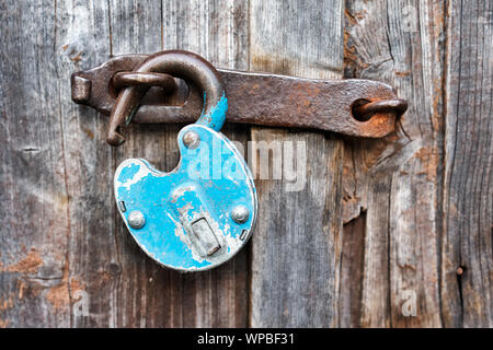 Blue vecchio arrugginito lucchetto aperto su una porta di legno Foto Stock