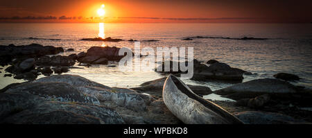 Sunrise vista lago Malawi, onde regolare scorrimento sulla spiaggia, legno one tree barca in primo piano, Africa, Panorama Foto Stock