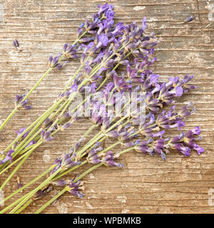 Immagine di quadri in stile rustico con chiusura del mazzetto di belli freschi di fiori di lavanda sulla vecchia superficie ruvida in legno naturale la superficie del tavolo. Consente di visualizzare Foto Stock