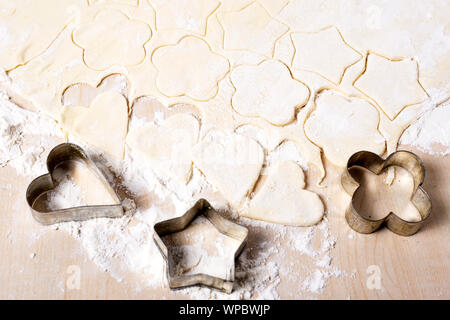 La cottura di biscotti a forma di cuore, stella e fiore su un bianco tavolo in legno Foto Stock