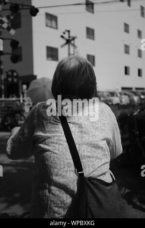 MATSUYAMA, Giappone - Lug 25, 2019: una scala di grigi selettivo verticale closeup colpo di una vecchia donna con capelli corti Foto Stock