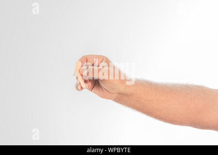 Mano d'uomo tenendo un Band-Aid su uno sfondo bianco. Spazio per scrivere. Foto Stock