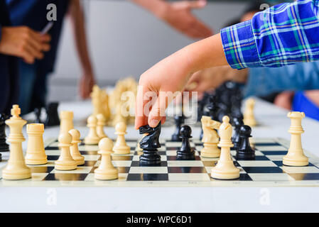 Bambino la mano si muove il cavallo durante un torneo di scacchi con diverse schede di gioco. Foto Stock