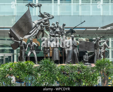 Manila, Filippine - Marzo 5, 2019: gruppo di Bronzo statua di abbandonata la gente intorno e su un serbatoio militare con una vittoria effige di donna con torcia stan Foto Stock