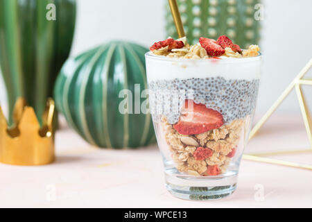 Pernottamento chia budino di sementi con latte di mandorla, yogurt, muesli fatti in casa, essiccato di fragole e mandorle in un bicchiere. Super e cibo vegan concetto. C Foto Stock