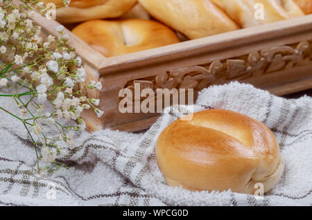 Mini bagel semplici nel cesto di legno e fiori. Foto Stock