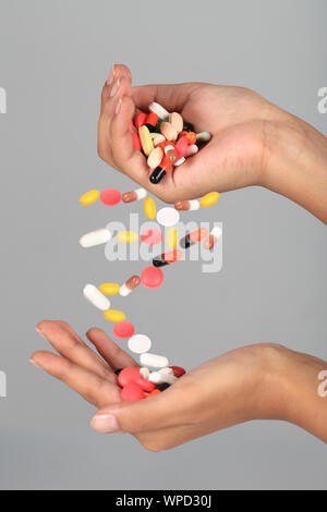 Primo piano di una mano di una persona che versa pillole su un'altra mano Foto Stock