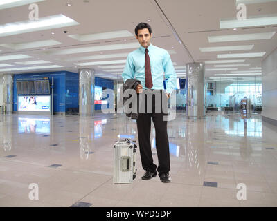 Uomo d'affari in piedi in un terminal aeroportuale Foto Stock