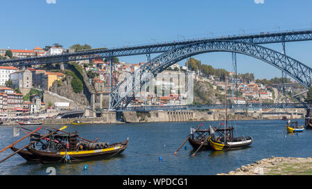 Porto, Portogallo. Dom Luis I ponte che attraversa il fiume Douro e collegamento di Vila Nova de Gaia, inferiore e Porto, parte superiore. Le barche, chiamato rabelos, una volta t Foto Stock