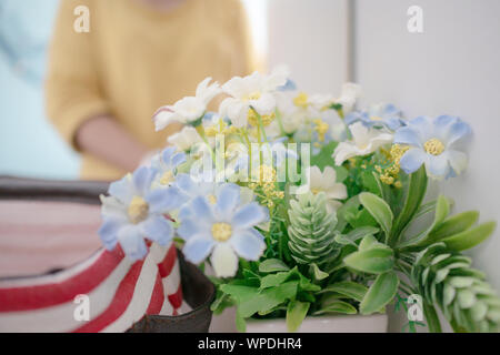 Chiudere su blur le donne allo specchio e fiori con il polline. Belle fioriture dei fiori finti e foglia verde con sfondo sfocato sul dressin Foto Stock