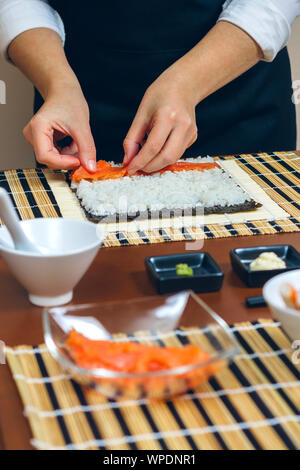 Chef ponendo le mani gli ingredienti sul riso Foto Stock