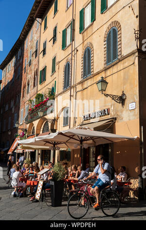 Un occupato Gelateria cafe bar al tramonto in Piazza San Michele, Lucca, Toscana, Italia. Foto Stock
