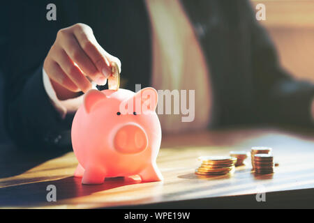 Chiudere l'attività femminile mettendo mano moneta nel salvadanaio Foto Stock