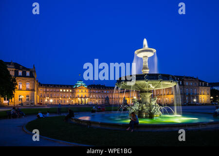 Stoccarda, Germania, 25 agosto 2019, fontane illuminate di fronte all'antico castello nuovo a schlossplatz square dopo il tramonto in estate dove molti pers Foto Stock