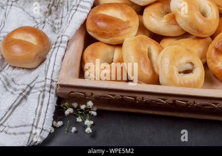 Piano bagel nel vassoio in legno con asciugamano bianco. Foto Stock