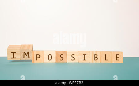Capovolgimento di due cubo di legno per cambiare la parola impossibile possibile su sfondo neutro Foto Stock