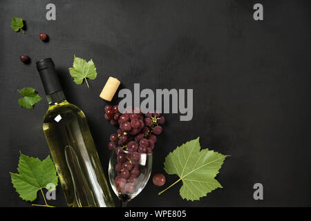 Flat-lay di una bottiglia, bicchieri da vino Uve fresche e sughero su sfondo nero, vista dall'alto, copia dello spazio. Wine bar, cantina e degustazione vino concept Foto Stock