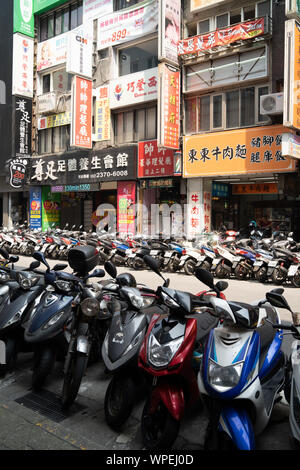 Densamente scooter parcheggiata su una strada nella città di Taipei, che racchiude la strada. Una visione comune in Taiwan. Foto Stock