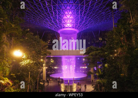 Incredibile pioggia Vortex a Changi gioiello centro per lo shopping in aeroporto Changi nella luce della sera con spettacolo di luci sulla cascata Foto Stock