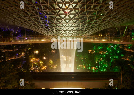 Incredibile pioggia Vortex a Changi gioiello centro per lo shopping in aeroporto Changi nella luce della sera con spettacolo di luci sulla cascata Foto Stock