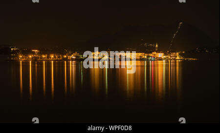 Un'esposizione lunga notte tempo colpo di riflessi di luce dagli edifici sulla piccola isola del lago di Isola Bella italiana sul lago Maggiore. Foto Stock