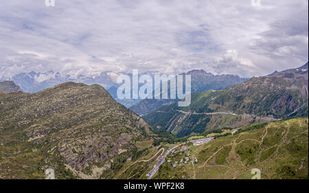 Una alta alpine Mountain Valley e strada di montagna pass. La strada passa attraverso delle alte cime montane e alpine ruvida terreno roccioso. Nuvole temporalesche forma ov Foto Stock
