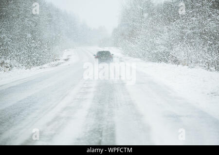La vettura si guida su una strada in inverno in una bufera di neve Foto Stock