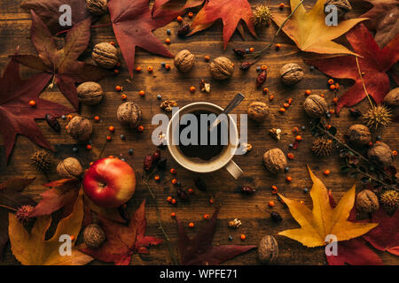 Autunno pausa caffè, tazza di una bevanda calda visto direttamente sopra con la stagione autunnale di frutta e foglie secche Foto Stock