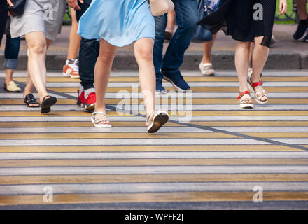 Pedoni che attraversano la strada a un crosswalk in città il giorno di estate Foto Stock