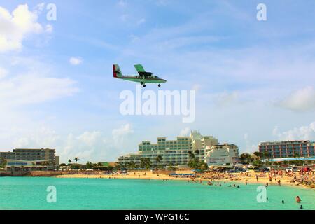 Un Winair De Havilland Canada DHC-6-300 piano PJ-WIU, vola basso su Maho beach come si arriva a terra a SXM Princess Juliana International Airport. Foto Stock