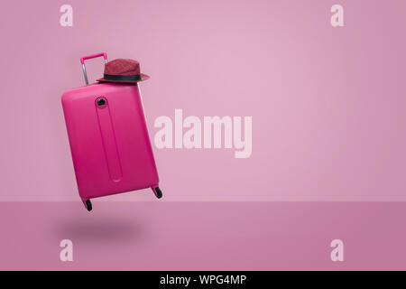 Valigia rosa con hat sul rosa pastello sfondo. concetto di viaggio. Stile minimal. Foto Stock